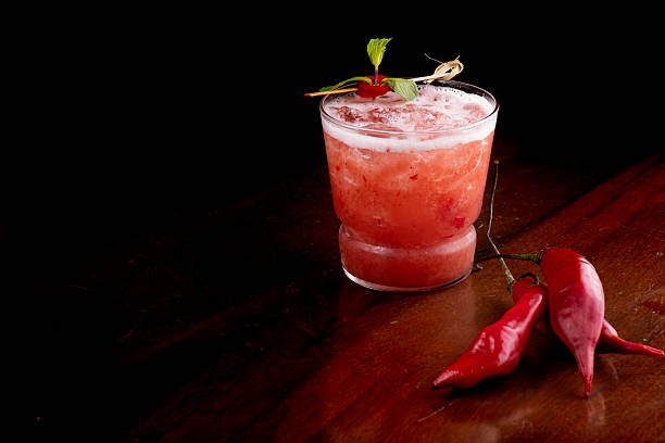 istock Spicy red cocktail with peppers and mint on a pub table at an angle with a black background 2212297561