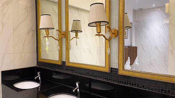 istock Vanity with gold framed mirrors and sconces shows black counter, close up. 2212301019