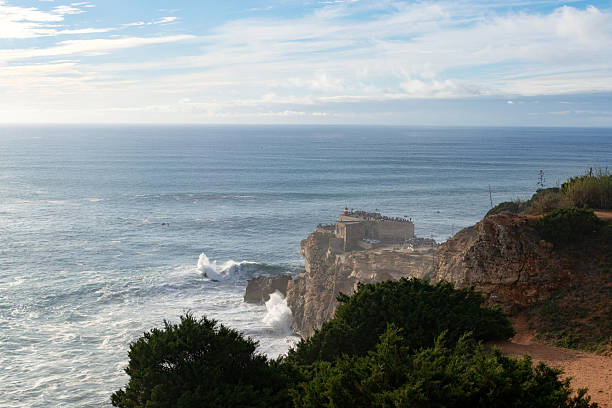 istock Dramatic coastal scene featuring a rocky cliff overlooking a vast ocean under a partly cloudy sky. Ideal for travel, nature, or seascape themed projects. Serenity meets power. 2212305774