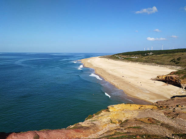 Breathtaking coastal view. Sandy beach meets the vast ocean under a clear blue sky. Serene, idyllic, perfect for travel, vacation, or nature themes. Inspiring landscape.