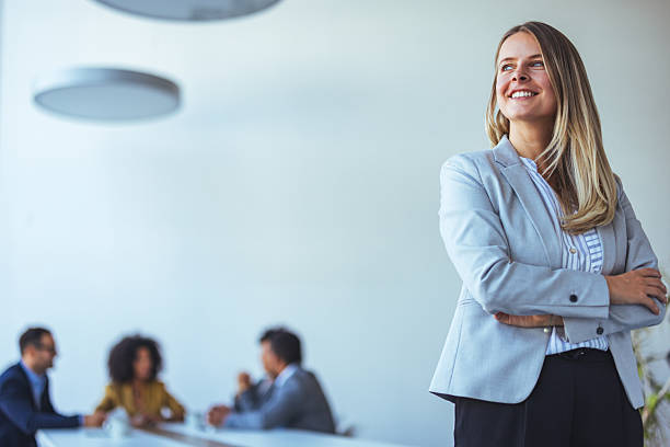 istock Confident Businesswoman Smiling in Modern Office Setting with Team Collaboration 2212312110