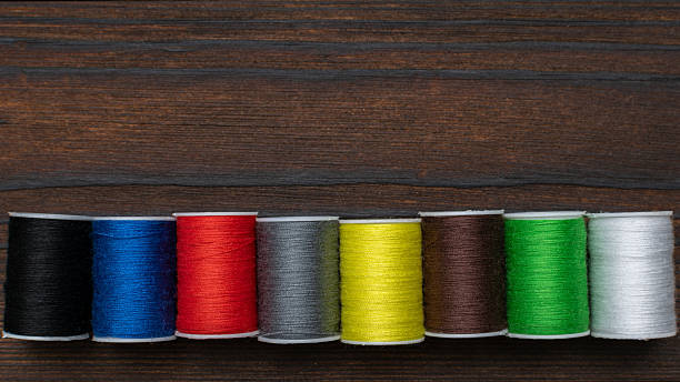 istock Colorful Sewing Thread Spools on Wooden Background for Craft and Fashion Projects 2212318258