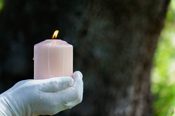 istock Gloved hand holding a lit pink candle in nature 2212319953
