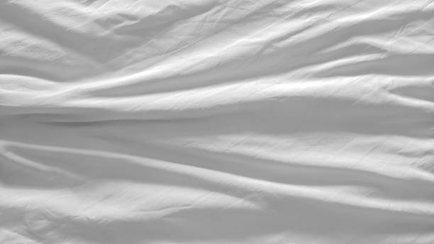 istock White and wrinkled bed sheet wave background. close up wave fabric. 2212320221