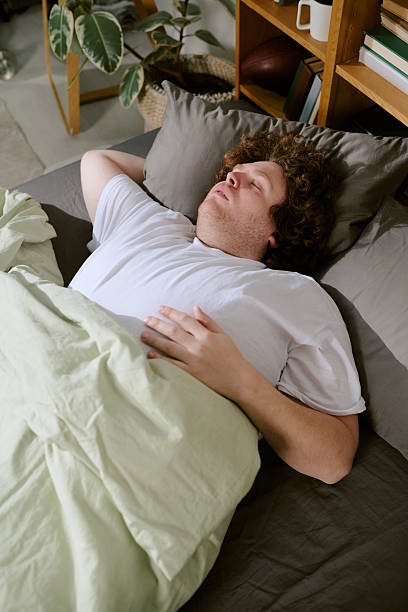 istock Sleeping Man Resting in Cozy Bed with Green Blanket 2212320696