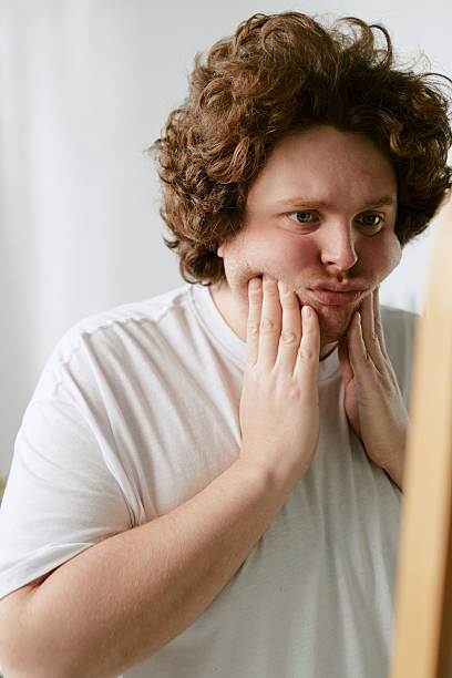 istock Young Man Wearing White Shirt Touching His Face in Thought 2212321958