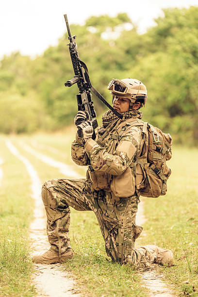 istock With tactical precision, the soldier crouches low, using the thick vegetation as cover while maintaining perfect aim and balance, a testament to his years of rigorous training. 2212322905