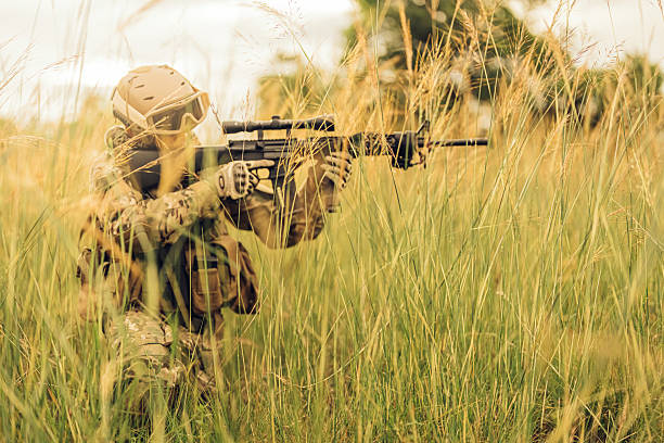 istock The soldier remains motionless, using the dense forest as cover while aiming his rifle toward an unseen threat, every movement precise and controlled through training and instinct. 2212322945