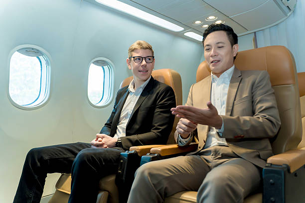 istock Two businessmen in formal suits having a professional conversation during a flight, seated in airplane cabin near window, business travel, collaboration, teamwork 2212325572