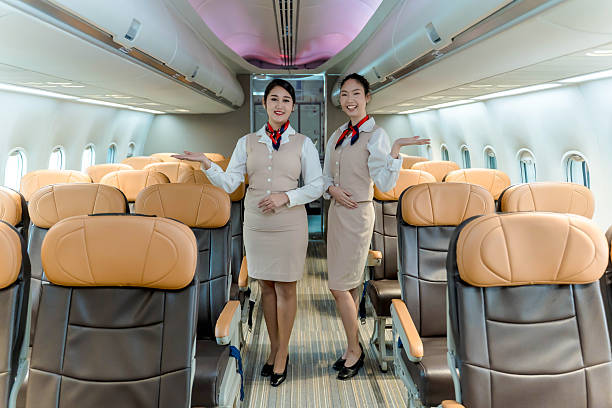 istock Professional airline flight attendants smiling and welcoming passengers onboard a commercial airplane, showcasing hospitality and safety inside aircraft cabin 2212325639