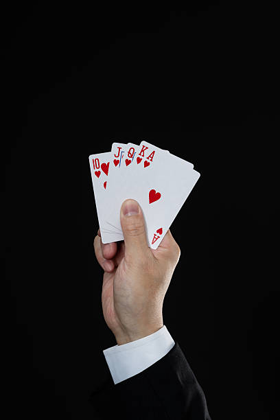 istock Businessman hand holding royal flush on black background 2212325744