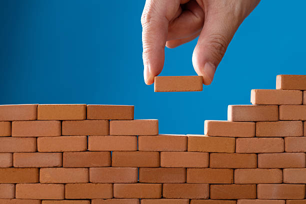 istock Man putting toy brick onto a wall 2212325914