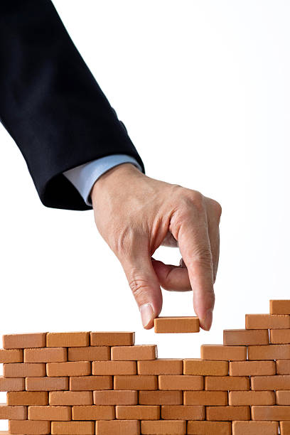 istock Businessman putting toy brick onto a wall 2212325924