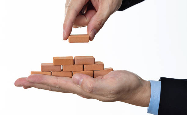 istock Businessman using toy brick build pyramid on hand 2212325928