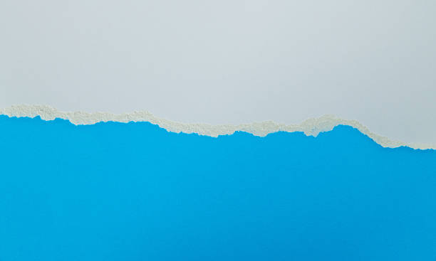 istock Tear white paper to reveal the blue background 2212325976