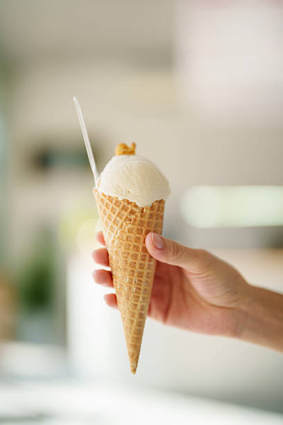 istock Hand Holding a Waffle Cone with Vanilla Ice Cream 2212326093