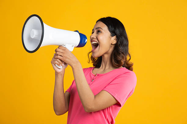 istock Woman shouting over megaphone on yellow background 2212326901