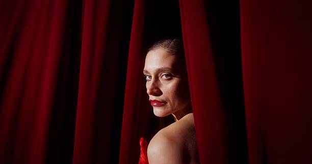 Young woman with long hair is posing under a red light in a studio