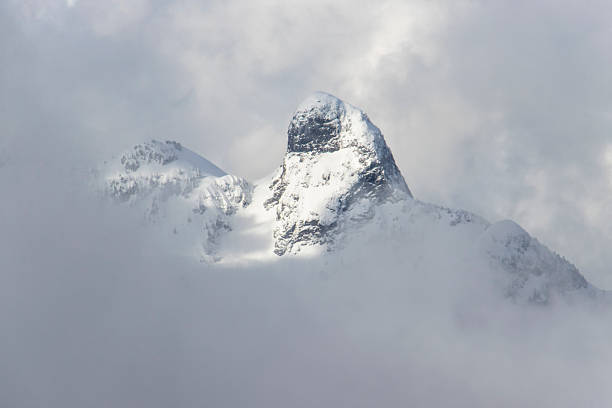 istock Majestic snow-capped mountain peak emerges through clouds in a serene landscape during a clear winter day 2212330400
