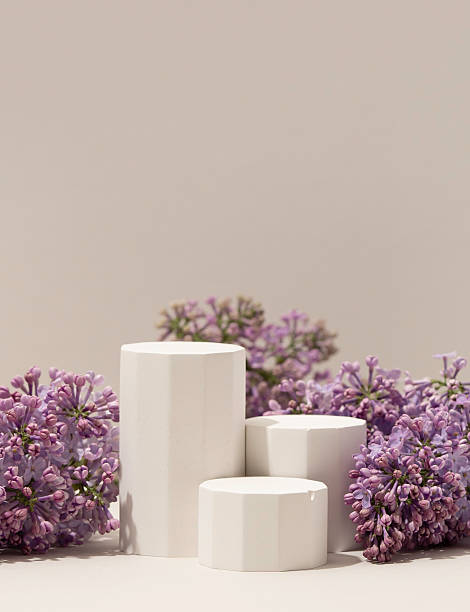 istock Elegant minimalistic spring-themed product display with white geometric pedestals surrounded by fresh lilac flowers on soft neutral background. Vertical photography. 2212330927