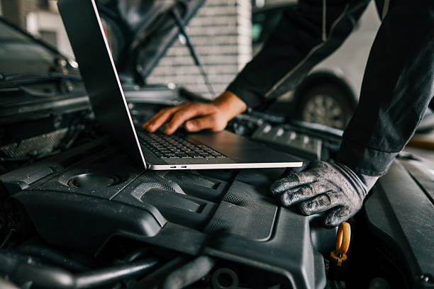 istock A mechanic using a laptop on a car engine for diagnostics in a garage. Highlights the use of technology in modern vehicle maintenance and repair 2212332306
