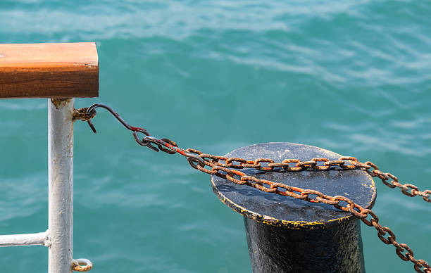 A detailed view of a critical marine element: the bollard, located on a wet wooden dock under sunlight. This image conveys maritime functionality and offers a nostalgic feeling of seaside moments.