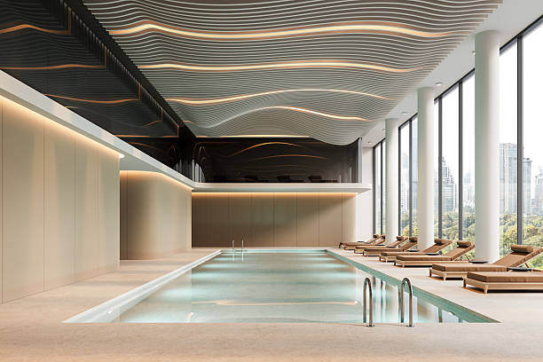 istock Modern luxury indoor swimming pool interior with relaxing loungers, wave-patterned ceiling, and panoramic city view through large glass windows. 3D Rendering 2212337268