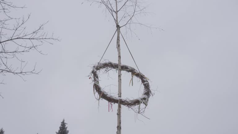 Raised maypole celebrating pagan gods in winter. Falling snow on a cold day. Prehistoric Czech village