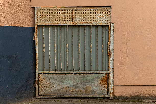 istock Rusty metal gate with vertical bars against a textured wall in an urban setting 2212339704