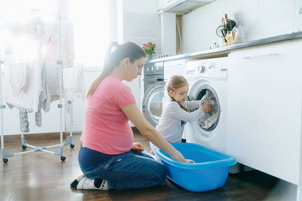 istock Mother and daughter doing laundry together in a bright modern home 2212339738
