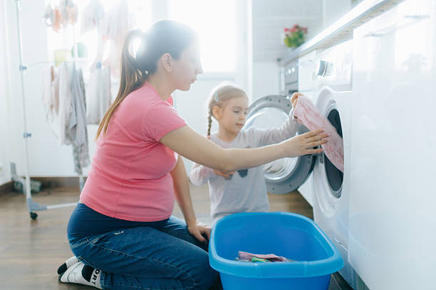 istock Mother and daughter doing laundry together in a bright home environment 2212339742