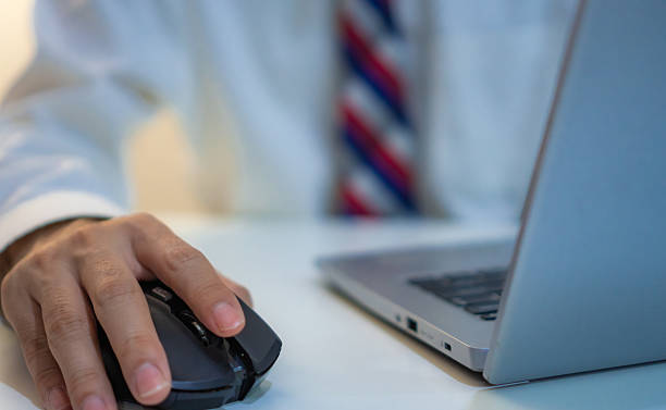 istock close up of person in formal attire using computer mouse while working on laptop, symbolizing productivity and focus in professional office environment 2212340593