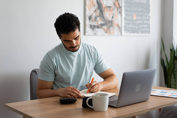 istock Young man concentrating on his budget, working from home 2212341104