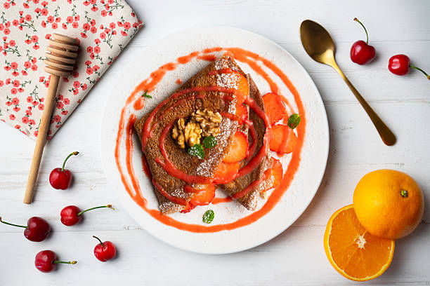 istock Chocolate crepes filled with strawberries and fruit sauce. Top view. 2212341524