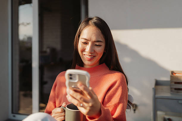 istock Beautiful Japanese woman using a smartphone while sitting on the balcony 2212342077