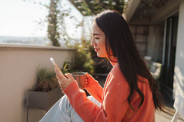 istock Beautiful Japanese woman using a smartphone while sitting on the balcony 2212342104