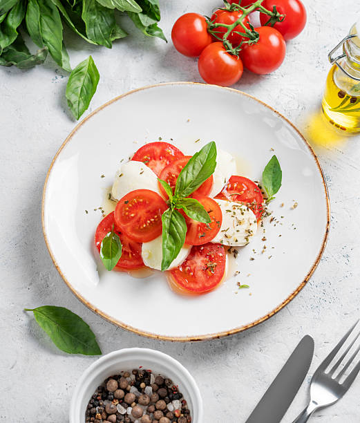 istock Caprese salad with sliced tomatoes, mozzarella and basil  on a light background 2212345802