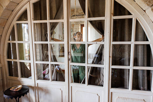 A lonely young girl looking thru the window in old, abandoned castle room.
