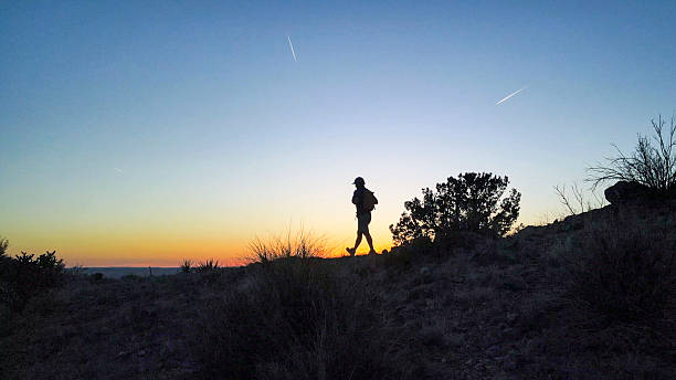 Side view of hiker following pathway in desert at dusk, White Ridge Trail, Albuquerque, New Mexico