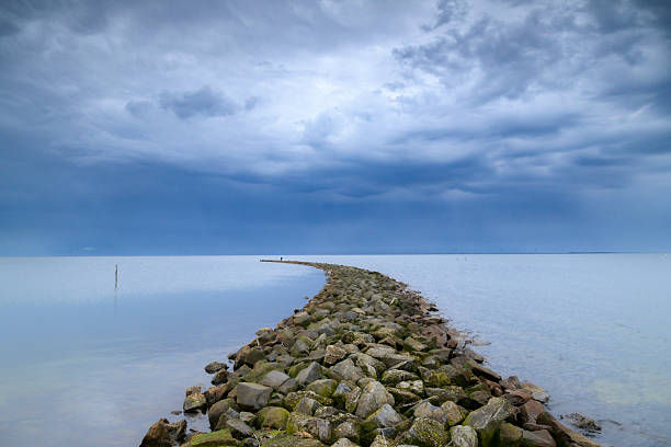 Lighthouse and village of the former Island of Urk alongside the lake IJsselmeer, long exposure with smooth water and dynamic sunset in the Netherlands