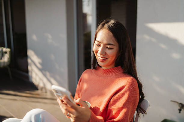 istock Beautiful Japanese woman using a smartphone while sitting on the balcony 2212352549