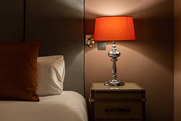 istock Cozy bedroom corner with chrome table lamp red lampshade and soft white bedding on gray wall 2212353385