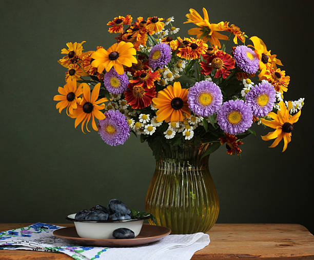 istock Colorful summer bouquet in glass vase with plums on rustic table 2212355172