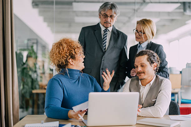 istock Senior company managers looking at laptop with two talented employees. 2212355426