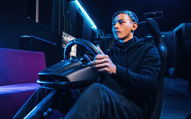 istock In the seat. Young guy is playing racing game by using driving simulator 2212359302