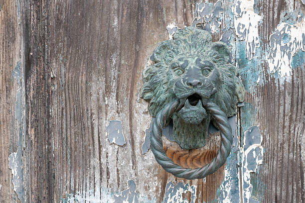 Antique lion head door knocker on old wooden door with rustic texture and peeling blue and white paint