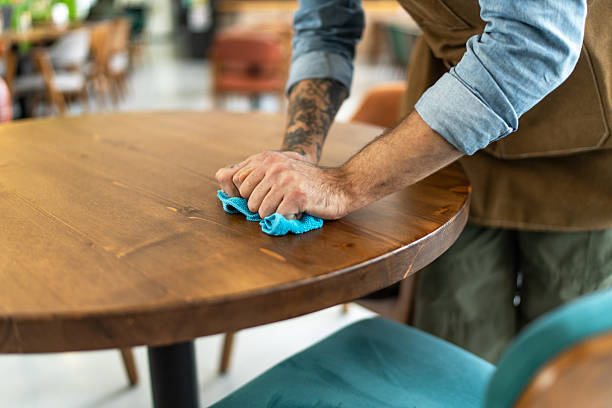 istock Waiter cleaning wooden table with blue cloth in restaurant 2212365499