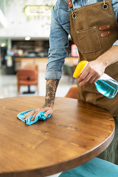 istock Waiter disinfecting tables at restaurant wearing apron 2212365571