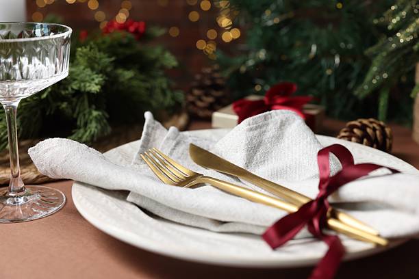 istock Christmas place setting with plate, napkin, cutlery and festive decor on brown table, closeup 2212370044