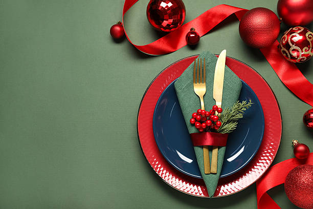 Christmas place setting with festive decor on green table, flat lay. Space for text